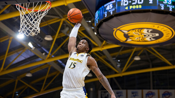 A Quinnipiac men's basketball player dunks the ball in the net in the basketball arena