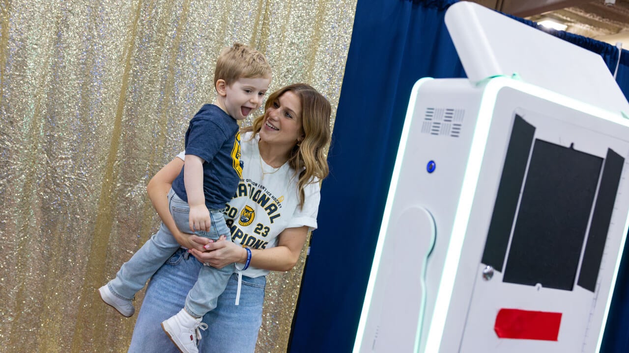 Person holds child smiling for a photobooth