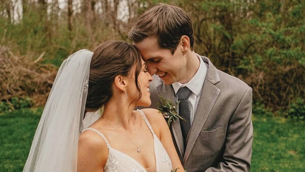 Lauren (Stalzer) Smith and husband embrace with a bouquet of white flowers