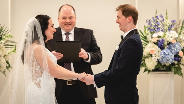 Meghan and Connor Aikens-Kinney hold hands while Justin Kile presides on a wedding alter
