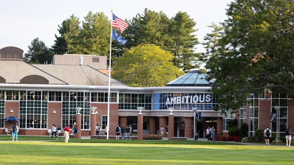 People walk in and out of the Quinnipiac student center with For the Ambitious logo in the windows